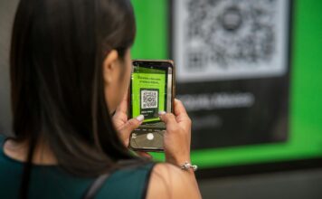 Jak wykorzystać kody QR w marketingu szeptanym i poleceniach między klientami Kobieta skanuje kod QR smartfonem na ulicy w Meksyku