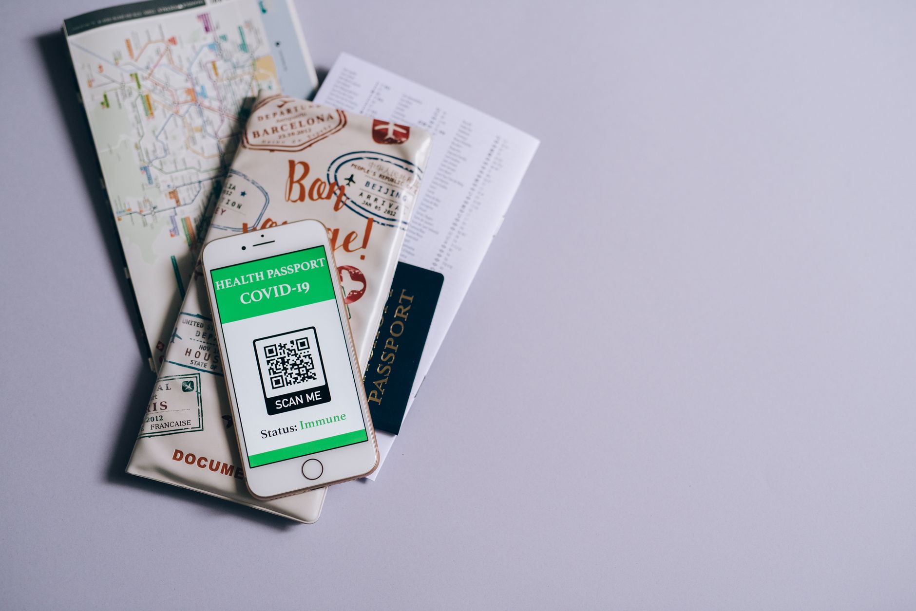 Smartfon z paszportem covidowym obok dokumentów podróżnych