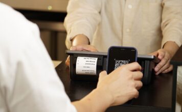 Kody QR na targach i eventach branżowych: od szybkich leadów po natychmiastową wycenę oferty Klienci przy sklepowej ladzie skanują kod QR do płatności bezgotówkowej